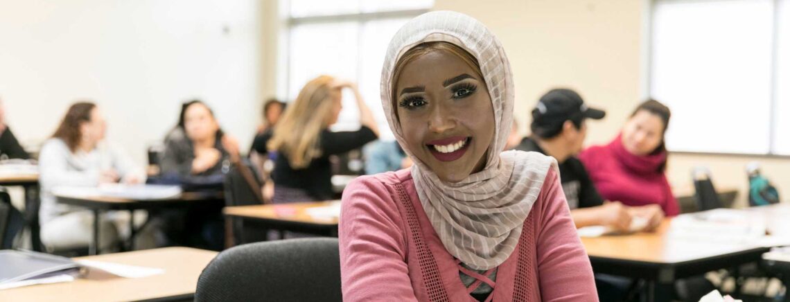 An ACC student smiles at the camera while attending an ESL class.